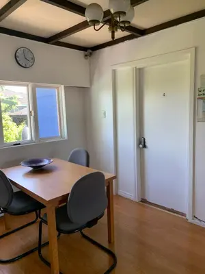 a dining room with a table and chairs and a clock at Vancouver Backpacker House - 10 min walk to Metrotown skytrain station in Burnaby