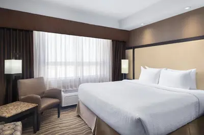 a hotel room with a large bed and a chair at Best Western Premier Freeport Inn Calgary Airport in Calgary