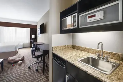 a kitchen with a sink and a room with a bed at Best Western Premier Freeport Inn Calgary Airport in Calgary