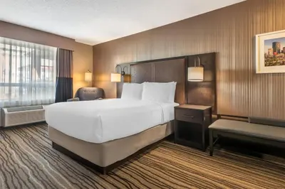 a hotel room with a large bed and a chair at Best Western PLUS Calgary Centre Inn in Calgary