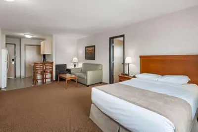 a hotel room with a large bed and a chair at Super 8 by Wyndham Grande Prairie in Grande Prairie