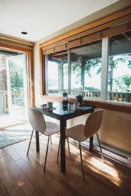 a dining room with a table and chairs and windows at The Shoreline Tofino in Tofino