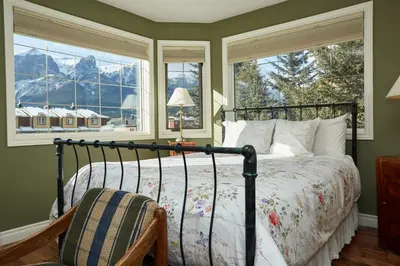 a bedroom with a bed and two windows at Lady MacDonald Country Inn in Canmore