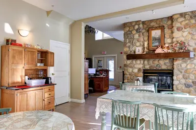 a kitchen with a stone wall with a table and chairs at Lady MacDonald Country Inn in Canmore