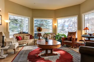 a living room with a table and chairs and windows at Lady MacDonald Country Inn in Canmore