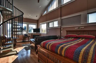 a bedroom with a large bed and a staircase at Birds of a Feather Victoria Oceanfront Studio Suites in Colwood