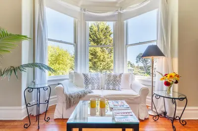 a living room with a white couch and a large window at Fairholme Manor Inn in Victoria