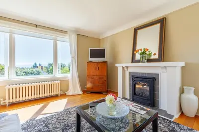 a living room with a fireplace and a tv at Fairholme Manor Inn in Victoria