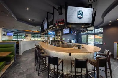a bar in a restaurant with chairs and televisions at Holiday Inn Victoria - Elk Lake by IHG in Victoria