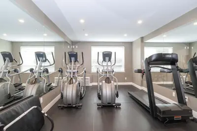 a gym with three elliptical machines in a room at Sandman Hotel Langley in Langley