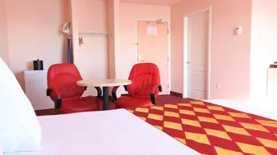a bedroom with two red chairs and a table and a bed at Crystal Star Inn Edmonton Airport with free shuttle to and from Airport in Leduc