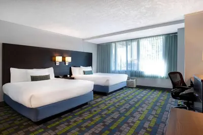 a hotel room with two beds and a television at Days Inn by Wyndham Victoria Airport Sidney in Sidney
