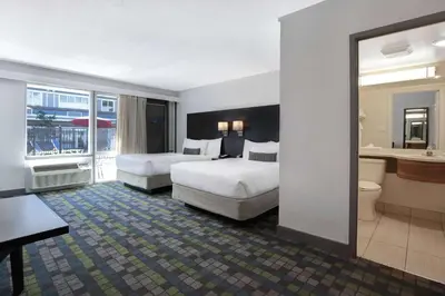 a hotel room with two beds and a bathroom at Days Inn by Wyndham Victoria Airport Sidney in Sidney