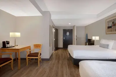 a hotel room with two beds and a desk at Days Inn by Wyndham Victoria Airport Sidney in Sidney