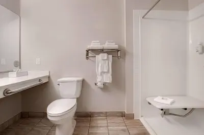 a white bathroom with a toilet and a sink at Days Inn by Wyndham Victoria Airport Sidney in Sidney