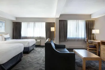 a hotel room with two beds and a desk at Days Inn by Wyndham Victoria Airport Sidney in Sidney