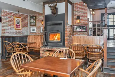 a restaurant with a fireplace and tables and chairs at The Bedford Regency Hotel in Victoria