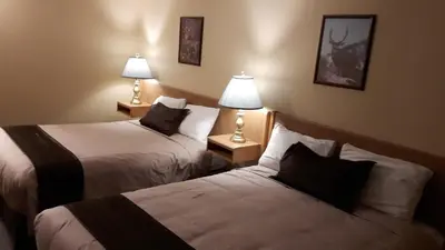 two beds in a hotel room with two lamps at Mary's Motel in Golden