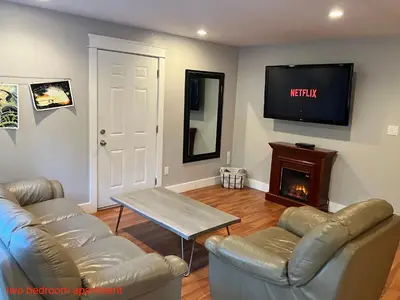 a living room with two leather couches and a tv at Sienna's Tree House (Tall Trees And Salty Breeze) in Tofino