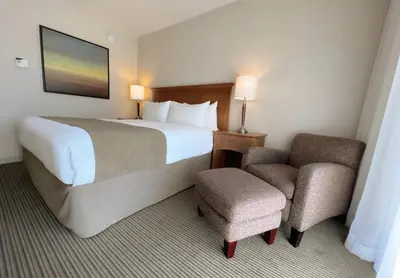 a hotel room with a bed and a chair at Coast Capri Hotel in Kelowna
