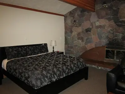 a bedroom with a bed and a stone wall at The Lodge At Skeena Landing in Terrace