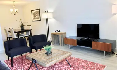 a living room with a flat screen tv and a table at Best Western Plus Regency Inn and Conference Centre in Abbotsford