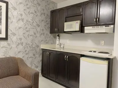 a kitchen with black cabinets and a microwave and a chair at Best Western Plus Regency Inn and Conference Centre in Abbotsford