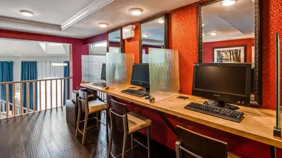 a room with a desk with a computer and chairs at Best Western Plus Regency Inn and Conference Centre in Abbotsford