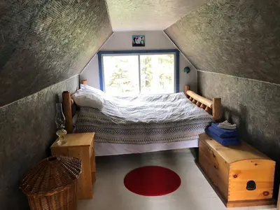 a small attic bedroom with a bed and a window at Vines and Puppies Hideaway in Jade City