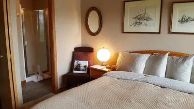 a bedroom with a bed and a lamp and a mirror at Reef Point Oceanfront Bed and Breakfast in Ucluelet