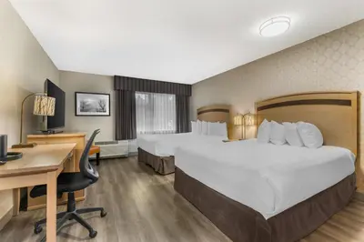 a hotel room with two beds and a desk at Best Western Plus Country Meadows Inn in Aldergrove