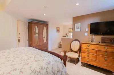 a bedroom with a bed and a dresser with a flat screen tv at Beaconsfield Bed and Breakfast - Victoria in Victoria