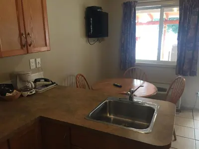 a kitchen with a sink and a table with chairs at Avalon Inn in Osoyoos
