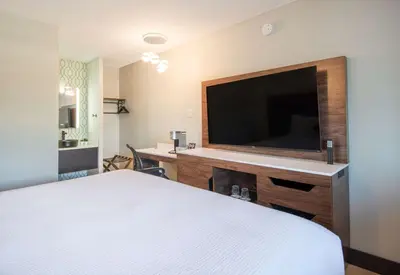 a hotel room with a bed and a flat screen tv at Coast Courtenay Hotel in Courtenay
