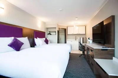 a hotel room with two beds and a kitchen at Coast Courtenay Hotel in Courtenay