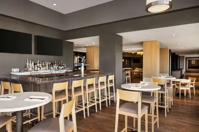 a restaurant with tables and chairs and a bar at Hilton Vancouver Airport in Richmond