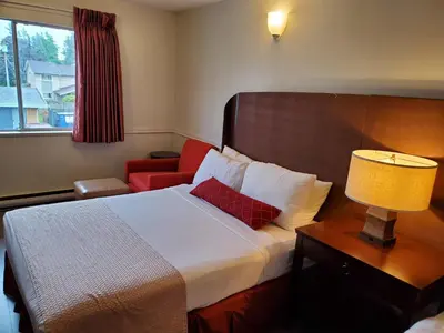 a hotel room with a bed and a red chair at Alpine Inn Abbotsford in Abbotsford