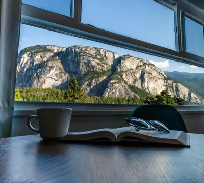 a book on a table with a cup and pair of glasses at August Jack Inn in Squamish