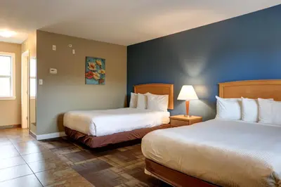 a hotel room with two beds and a blue wall at Vedder River Inn in Chilliwack