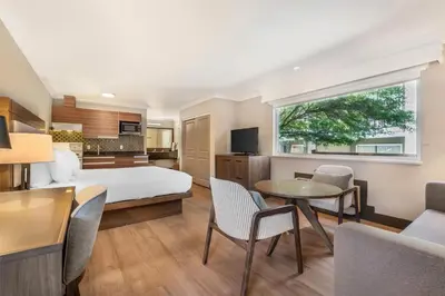 a hotel room with a bed and a table and chairs at Best Western PLUS Burnaby Hotel in Burnaby
