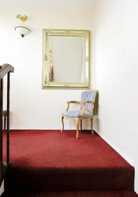 a chair in a room with a red carpet and a mirror at Heron's Landing Hotel in Campbell River