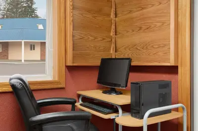 a desk with a computer monitor and a chair at Travelodge by Wyndham Quesnel BC in Quesnel