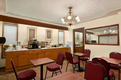 a restaurant with tables and chairs and a kitchen at Travelodge by Wyndham Quesnel BC in Quesnel
