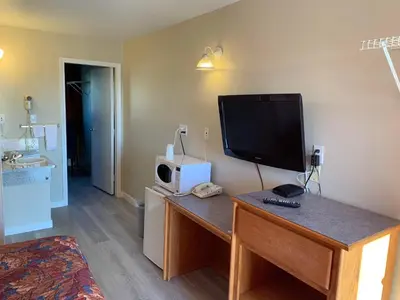 a living room with a tv and a desk with a television at Red Deer Inn & Suites in Red Deer
