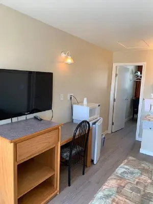 a room with a desk with a flat screen tv at Red Deer Inn & Suites in Red Deer