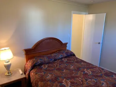 a bedroom with a bed and a table with a lamp at Red Deer Inn & Suites in Red Deer