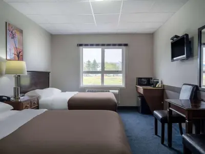a hotel room with two beds and a desk and a television at Travelodge by Wyndham Wetaskiwin in Wetaskiwin
