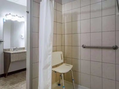 a bathroom with a chair and a shower curtain at Travelodge by Wyndham Wetaskiwin in Wetaskiwin
