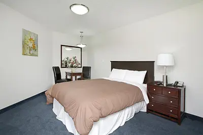 a bedroom with a large bed and a desk and a table at Travelodge by Wyndham Wetaskiwin in Wetaskiwin
