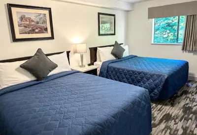 two beds in a hotel room with blue sheets at Canadian Inn in Surrey